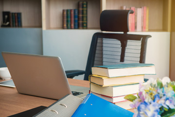 Book stack and laptop on table in office