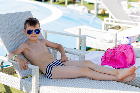 Young boy in a swimsuit on a shelf by the pool