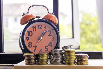 Clock and coins with the word SAVING - the concept of savings