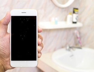 Human hand holding wet smart phone in water closet with copy space. Water damage, waterproof concept.