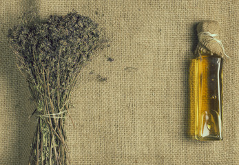 Bouquet of Dried Thyme and Oil Bottle on Sackcloth Background