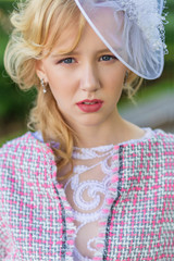 Portrait of a young blonde in a pink suit in a park outdoors.