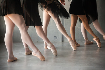 close-up of a young ballet dancer in black dresses, white pantyhose and pointe shoes pull a sock