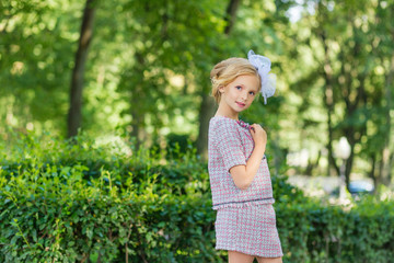 Portrait of a blonde in pink attire in a park outdoors.