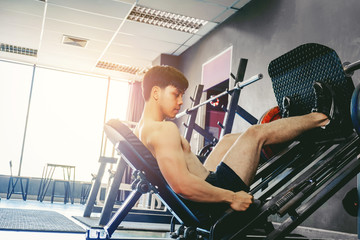 Fitness young man exercising using rowing machine in the gym