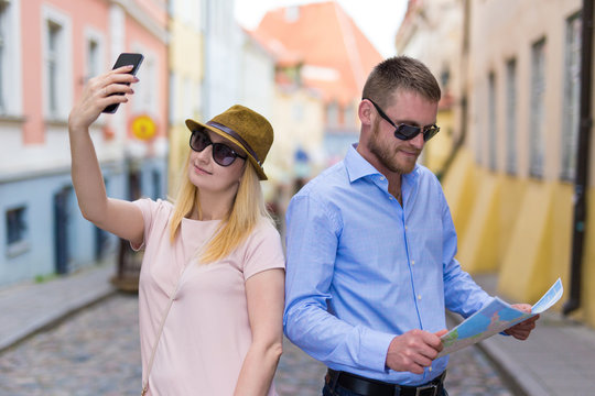 travel and tourism concept - man with city map and woman taking photo with smart phone