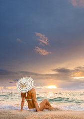 Fototapeta na wymiar Woman in bikini and straw hat on the beach
