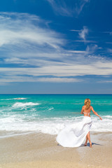 Fototapeta na wymiar Young woman standing on a beach and enjoying the sun