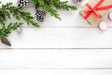 Christmas background. Christmas frame made of fir leaves, pine cones, gift box, candle decoration rustic elements on white wooden. Creative flat lay, top view design