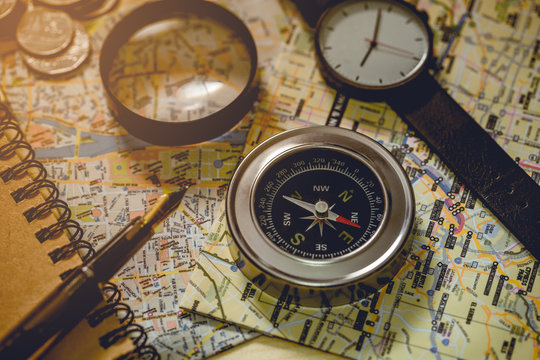The compass is placed on a city map with objects nearby. Tone of photo is vintage style.