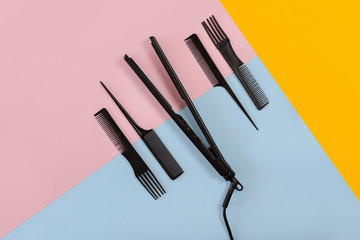 Various hair styling devices on the color blue, yellow, pink paper background, top view