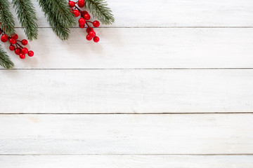 Christmas and New year background with fir branches and holly berry on white wooden background. ...