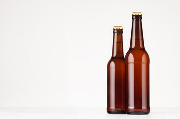 Two brown longneck beer bottles 500ml and 330ml mock up. Template for advertising, design, branding identity on white wood table.