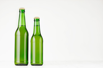 Set of two green longneck beer bottles 330ml, mock up. Template for advertising, design, branding identity on white wood table.