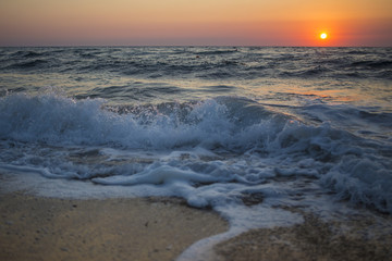 Obraz premium Il sole che tramonta nel mare è sempre una bella chiusura per una giornata di vacanza. Le tonalità calde donate dal sole si scontrano con il blu delle acque agitate del mare.