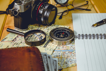 The compass is placed on a city map with objects nearby. Tone of photo is vintage style.