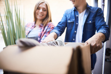 Obraz premium Portrait of smiling man and woman putting cardboard box into moving van