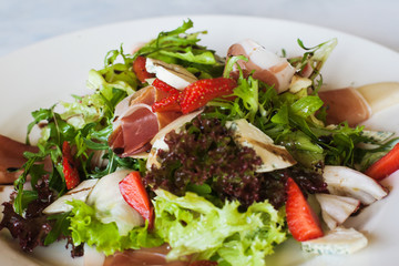 Salad lettuce with parma ham, blue cheese and strawberry serving in restaurant. Gourmet cuisine, close up picture