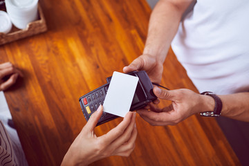Top view of female hand holding credit card paying with wooden counter in background