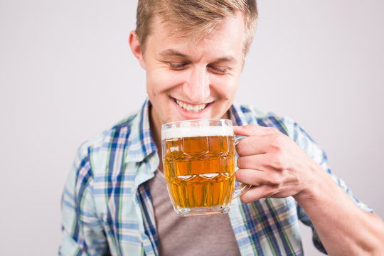 Cheerful Young Man Holding A Beer Mug Full Of Beer And Smiling On White Background