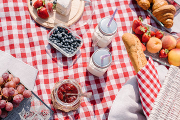 Picnic in the nature with croissants, peaches, strawberries, blueberries, grapes, baguette, cheese...