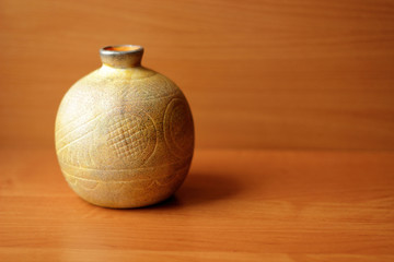 Yellow spherical vase on the wooden background