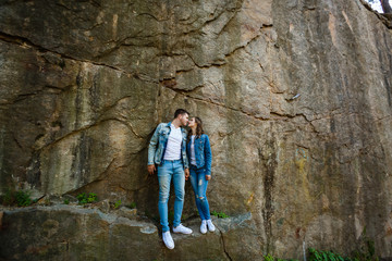 Obraz premium Man and woman standing arm in arm on a rock, sunset