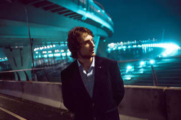 Fototapeta premium Young stylish guy on the background of night city, city lights