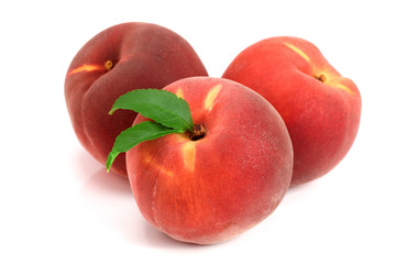 Three peaches with green leaf isolated on white background