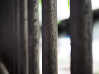 Old rusty dirty grey iron steel cylinder pole fence wall, perspective, blurred white background, focused at the center