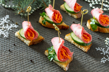 Appetizer canape on crispy bread with cucumber, carrots and sausage. Beautiful Christmas and New Year's food background. Selective focus.