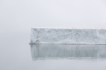 Iceberg floats in the polar sea of ​​Svalbard on a foggy day, Spitsbergen, Norway