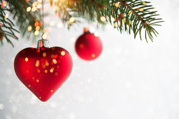 Red christmas ornaments, heart and ball, on the xmas tree on glitter bokeh background with twinkle...