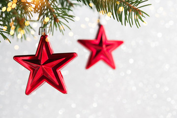Red christmas ornaments, stars, on the xmas tree on glitter bokeh background with twinkle lights....