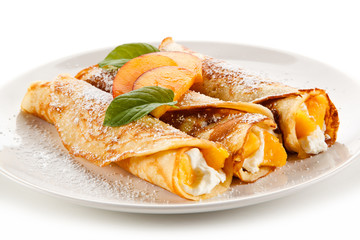 Crepes with peaches and cream on white background 