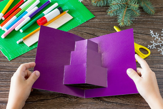 The child adds a birthday card with Christmas presents. Made by own hands. Children's art project, craft for children. Craft for kids.