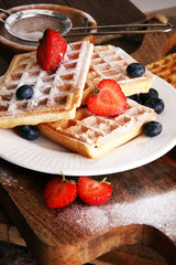 Homemade waffles with berries in plate on wooden table
