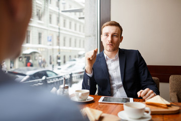 Serious man listening to his colleague during lunch in cafe