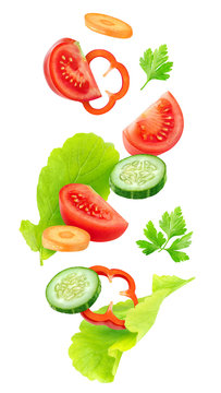 Fototapeta Isolated vegetables mix. Pieces of fresh tomato, cucumber, carrot, bell pepper and lettuce leaves (salad ingredients) in the air isolated on white background with clipping path