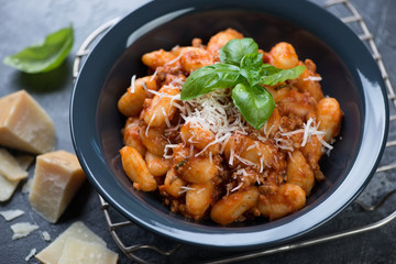 Closeup of italian potato gnocchi with meat sauce and parmesan cheese, selective focus