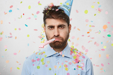 Unhappy birthday guy with stubble feeling sad and disappointed because nobody came to celebrate his...