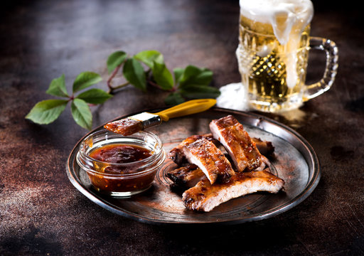 Grilled pork baby ribs with barbecue sauce and a mug beer