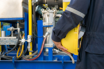 Fototapeta premium Worker engineer Man work in oil or gas refinery, turning on and off the pipeline valve torso and hand engineer yellow helmet for workers security construction worker .