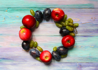 Apples, plums and grapes on a soft blue background