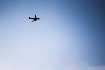 Airplane flying in the blue sky silhouetted.