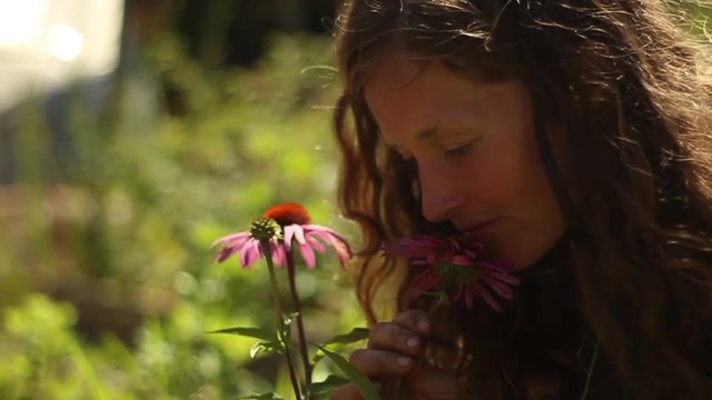 Woman smells echinacea flowers, slow motion, in a beautiful garden on Vancouver Island, Canada, narrow Depth of Field