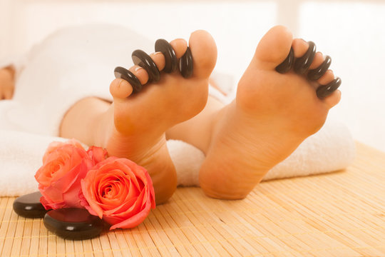Woman receiving hot stone massage on feet. Isolated.