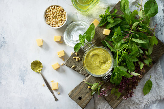 Green pesto sauce, basil, parmesan and pine nuts on a stone or slate table. Healthy Italian cuisine. Copy space.