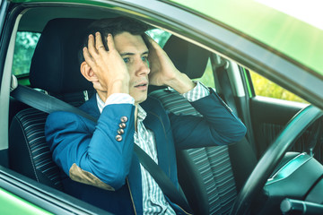 Man driver sitting in the car clutching his head. Concept of accidents on the road and dangerous...