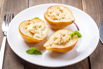 Pears baked with Ricotta cheese, nuts, honey and cinnamon on rustic wooden background